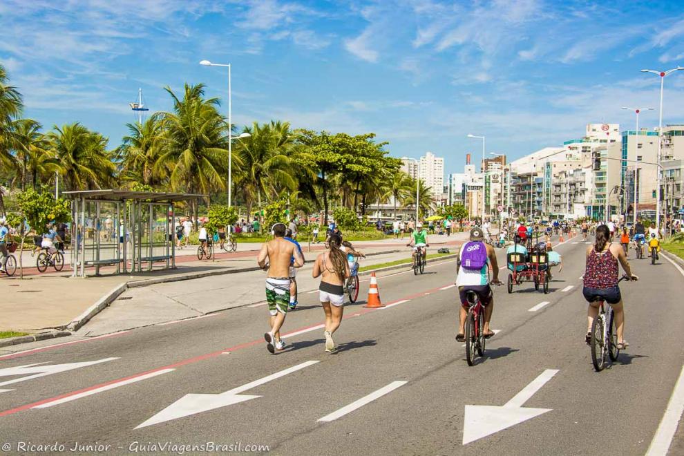 Imagem de pessoas andando de bicicleta e correndo na avenida na Praia de Cambori.